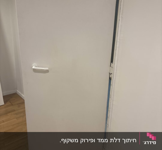 דלת פתוחה עם ידית לבנה על רצפת עץ
